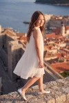 Plisseekleid Rozalia in Weiß auf der Stadtmauer – Seitenansicht