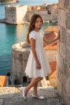 Kleid Rumi in Weiß mit Tulpenärmeln – im Freien vor einer Steinmauer